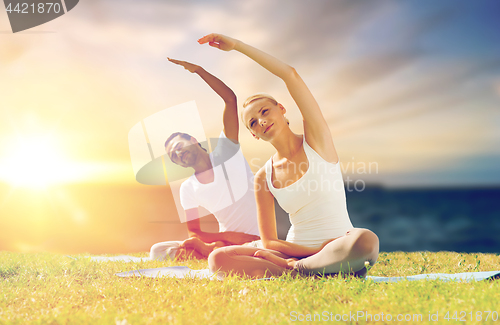 Image of couple making yoga exercises outdoors