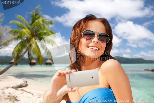 Image of woman taking selfie by smartphone on beach