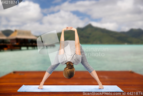 Image of woman making yoga wide-legged forward bend outdoor