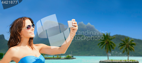 Image of woman taking selfie by smartphone on bora bora