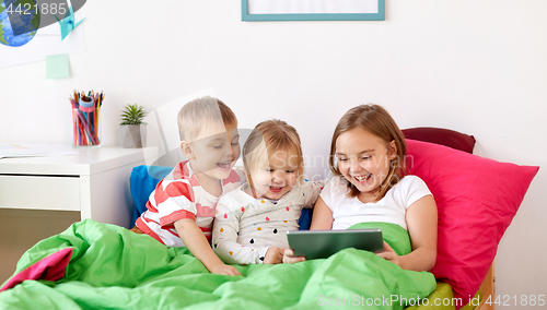 Image of little kids with tablet pc in bed at home