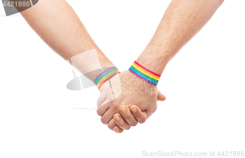 Image of hands of couple with gay pride rainbow wristbands