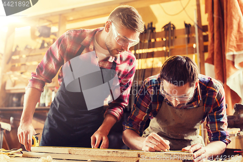 Image of carpenters with ruler and wood plank at workshop