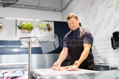 Image of seller weighing fish on scale at seafood shop