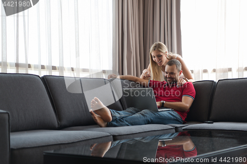 Image of couple using laptop at home