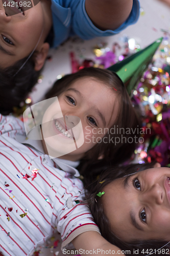 Image of kids  blowing confetti while lying on the floor