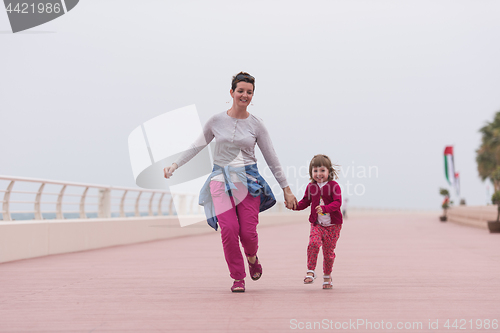 Image of mother and cute little girl on the promenade by the sea