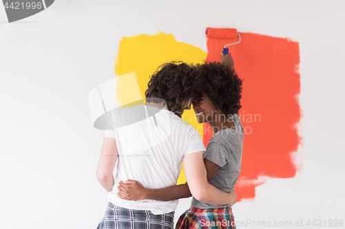 Image of multiethnic couple painting interior wall