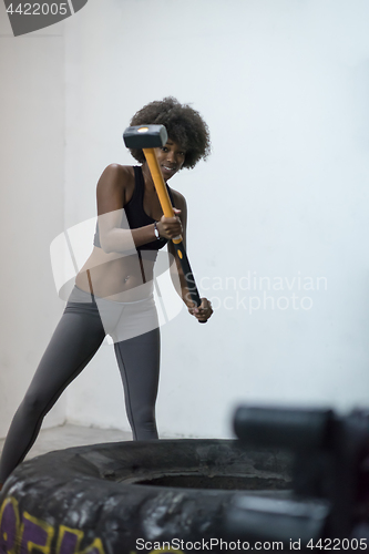 Image of black woman workout with hammer and tractor tire