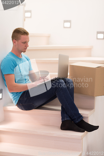 Image of young man sitting in stairway at home