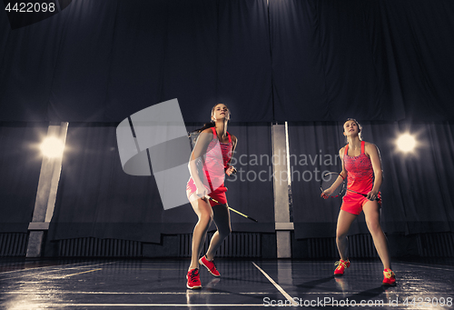 Image of Young women playing badminton at gym