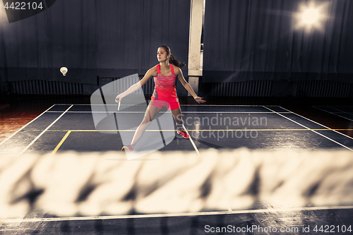 Image of Young woman playing badminton at gym