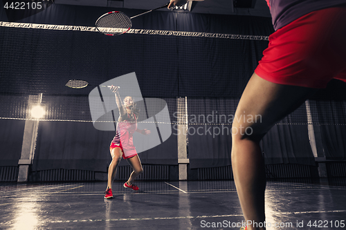 Image of Young woman playing badminton at gym