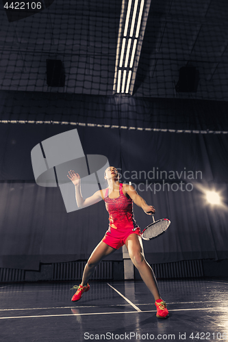 Image of Young woman playing badminton at gym