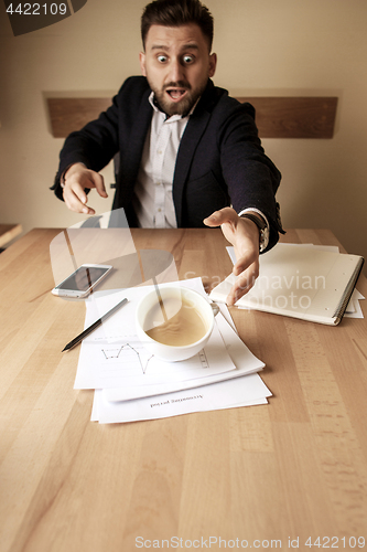 Image of Coffee in white cup spilling on the table in the morning working day at office table