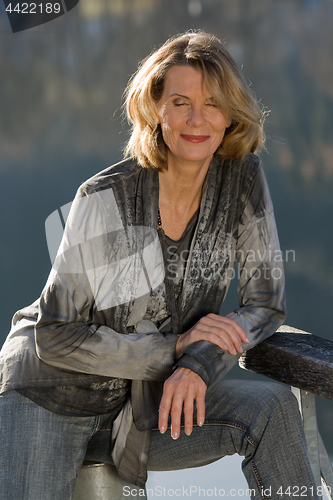 Image of elderly lady in fashionable blouse enjoys the sunshine in your face