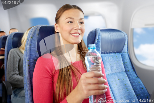 Image of happy young woman with water bottle in plane