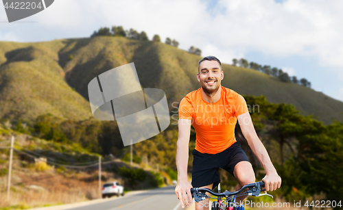 Image of happy young man riding bicycle over big sur hills