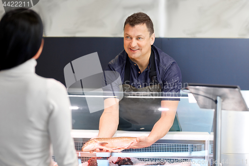 Image of seller showing seafood to customer at fish shop