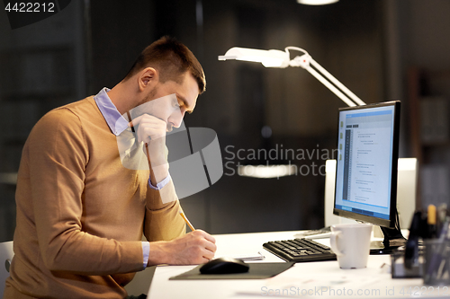 Image of man with notepad working on code at night office