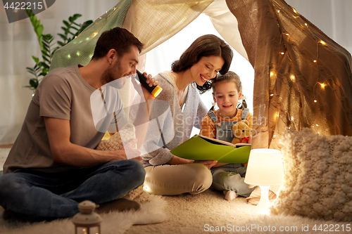 Image of happy family reading book in kids tent at home