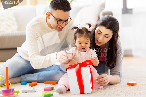 Image of baby girl with birthday gift and parents at home 