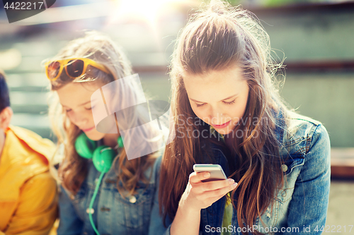 Image of happy teenage friends with smartphones outdoors