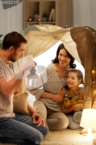 Image of happy family playing in kids tent at night at home