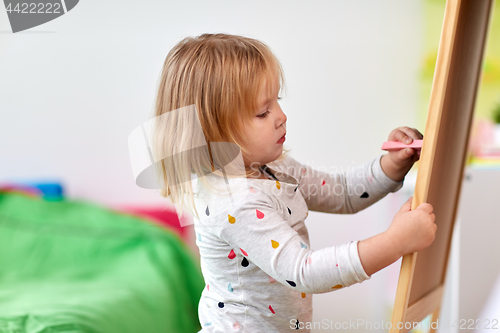 Image of happy little girl drawing on chalk board at home