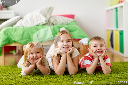 Image of happy little kids lying on floor or carpet