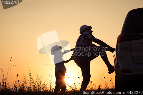 Image of Father and son playing in the park at the sunset time.