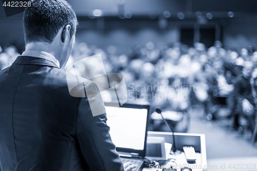 Image of Public speaker giving talk at business event.