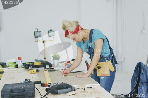 Image of Female carpenter drawing lines on plywood sheet 