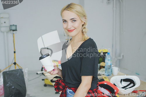 Image of Smiling female with paper cup in workshop 