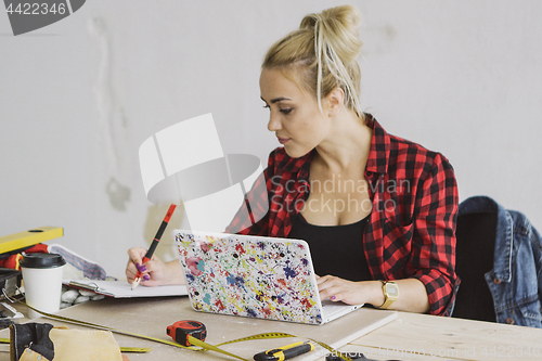 Image of Female with laptop writing in notebook 