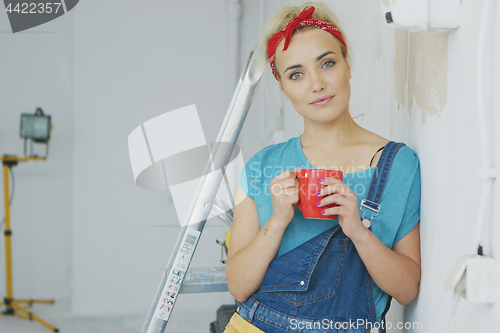 Image of Smiling female in overalls leaning on wall 