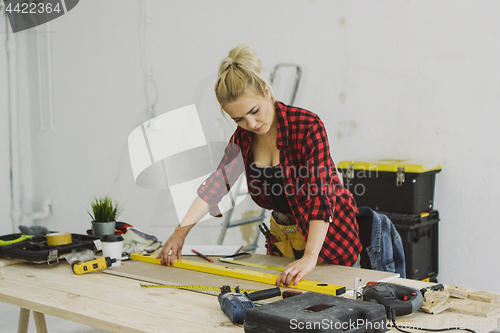 Image of Woman using spirit level on workshop desk 