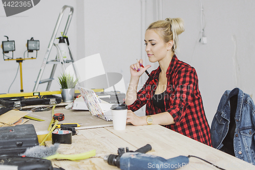 Image of Sitting at workbench female using laptop 