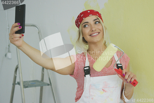 Image of Cheerful female taking selfie with paint roller