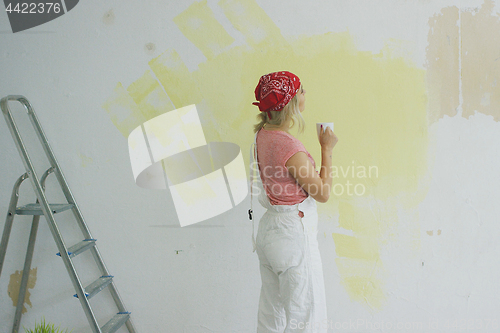 Image of Female painter with drink looking at wall