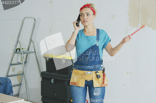 Image of Doing home repairs woman talking on smartphone 