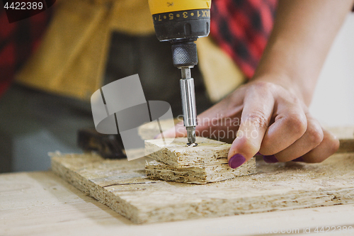 Image of Woman driving screw into chipboard with gun