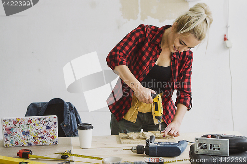 Image of Female drilling wooden plank on workbench 