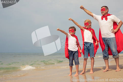 Image of Father and children playing superhero on the beach at the day ti