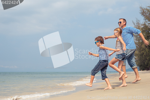 Image of Father and children  playing on the beach at the day time.