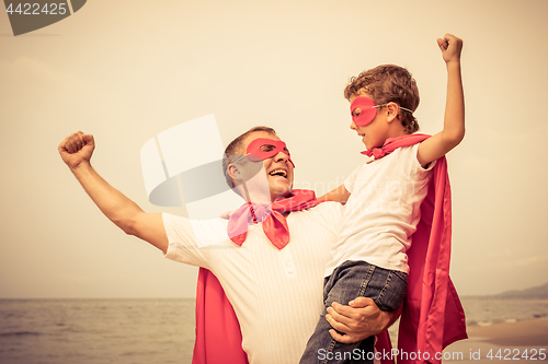 Image of Father and son playing superhero on the beach at the day time.