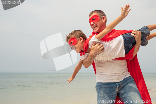 Image of Father and son playing superhero on the beach at the day time.