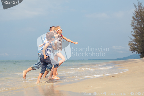 Image of Father and children  playing on the beach at the day time.