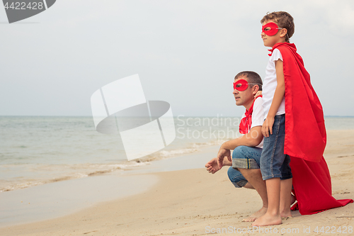 Image of Father and son playing superhero on the beach at the day time.