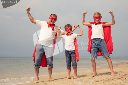 Image of Father and children playing superhero on the beach at the day ti